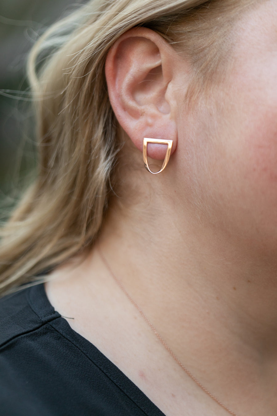 Chouette Designs a close up of a blond woman's ear with a twist earring in rose gold