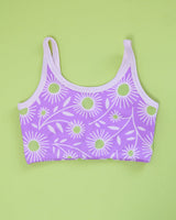 Flat lay product shot showing the back view and scoop neck design of the purple Delia's Daisy longline bra on a green backdrop.