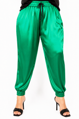 Front view close-up of a model wearing high-waisted emerald green Italian silk jogger pants with a black drawstring waist and elastic cuffed ankles.