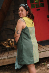 Three-quarter back profile showing the side pocket detail and yellow yoke contrast on the aloe green Beth Dress.