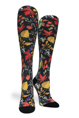 Studio shot of a pair of Crazy Compression Falls Back knee-high socks featuring an autumn leaf and botanical pattern on black fabric.