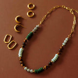 Overhead arrangement showing the Green Phoebe Gemstone Necklace alongside three pairs of gold hoop earrings.