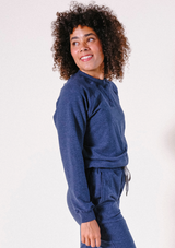 Side profile portrait of a model looking over her shoulder wearing the Poplinen Agnes Raglan Sweatshirt and matching lounge pants.