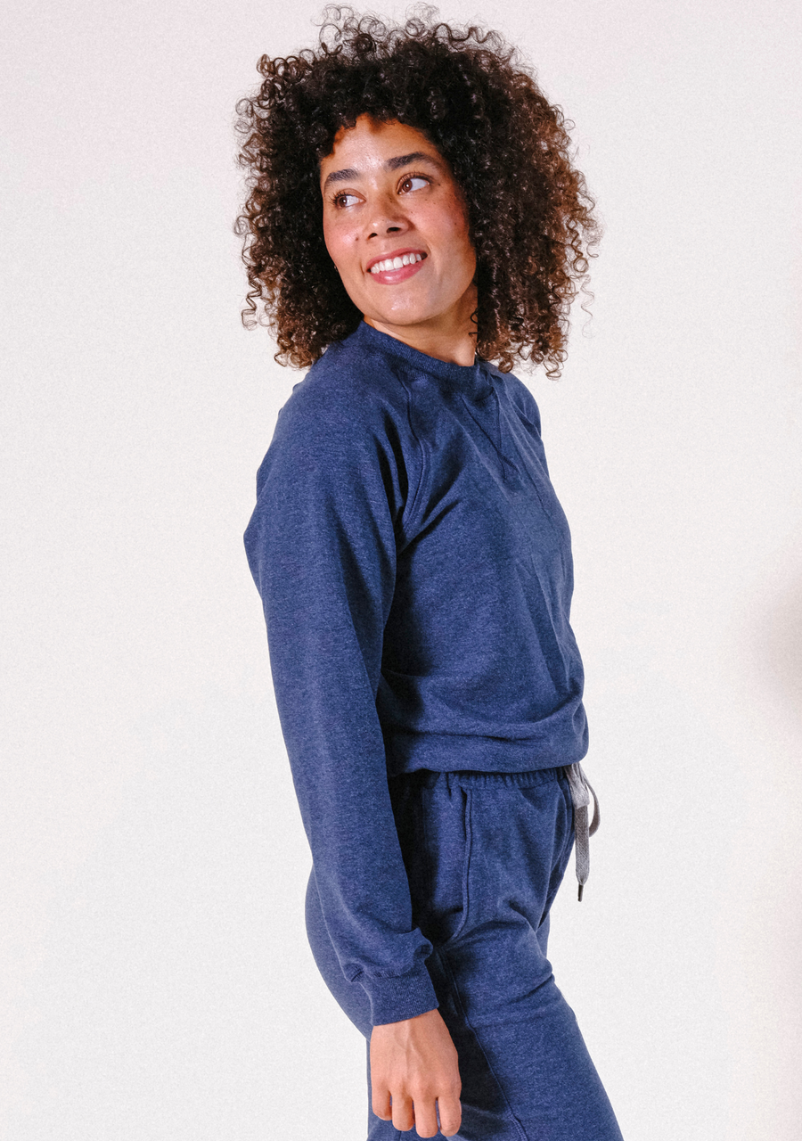 Side profile portrait of a model looking over her shoulder wearing the Poplinen Agnes Raglan Sweatshirt and matching lounge pants.