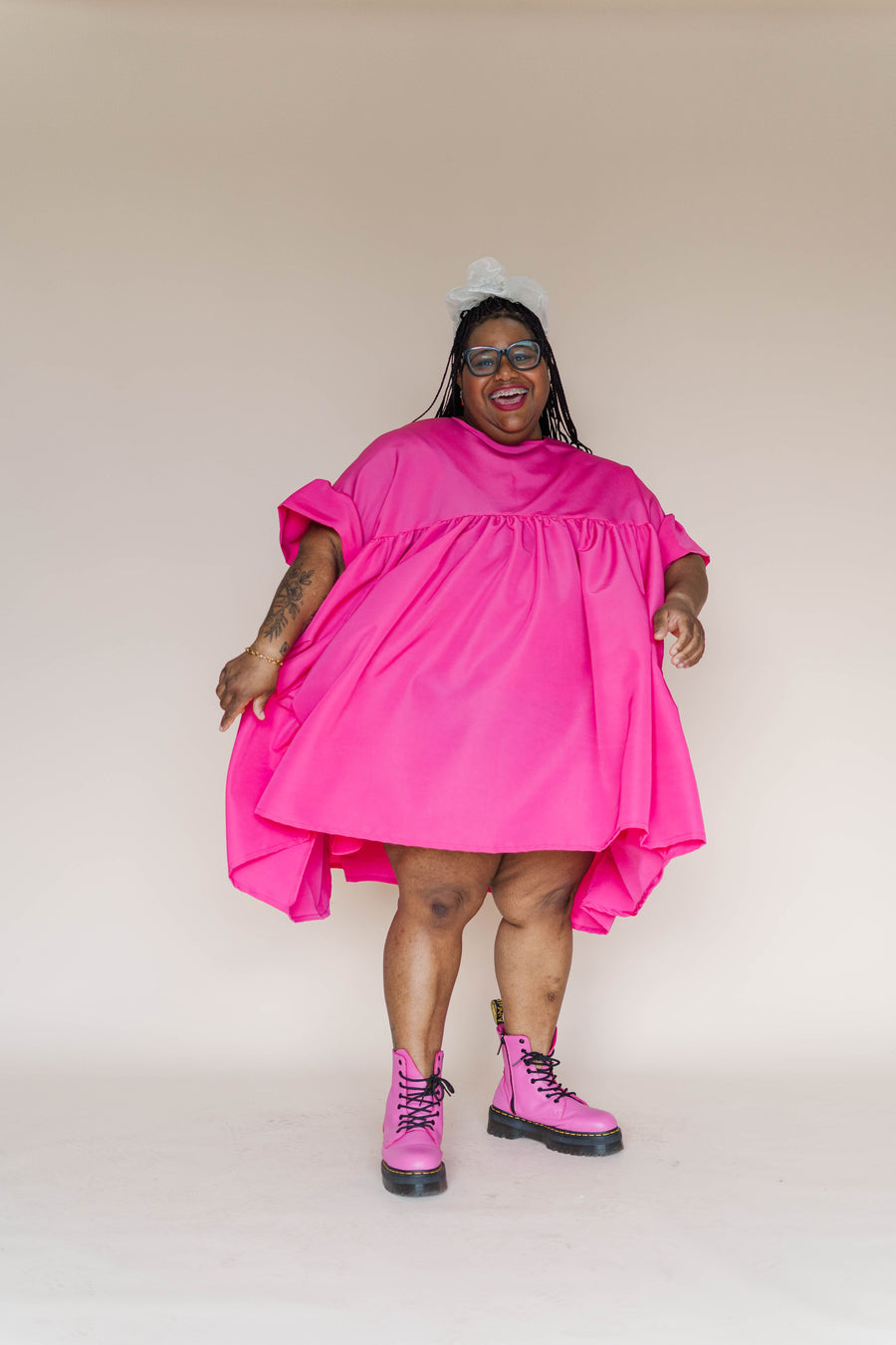 Front view portrait of a plus-size model smiling while wearing the hot pink taffeta Mini Mushroom Dress featuring short puff sleeves.