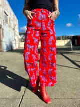 Cropped front view showing the wraparound utility pockets and high waist of the red NOOWORKS Skater Pant in pink leopard Sondler Cat print.