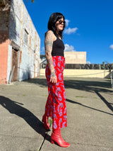Side profile view of the high-waisted red NOOWORKS Skater Pant showcasing the wide-leg drape and red leather ankle boots.