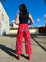 Rear view portrait showing the full-length wide-leg back coverage and fit of the red Sondler Cat printed twill pants.