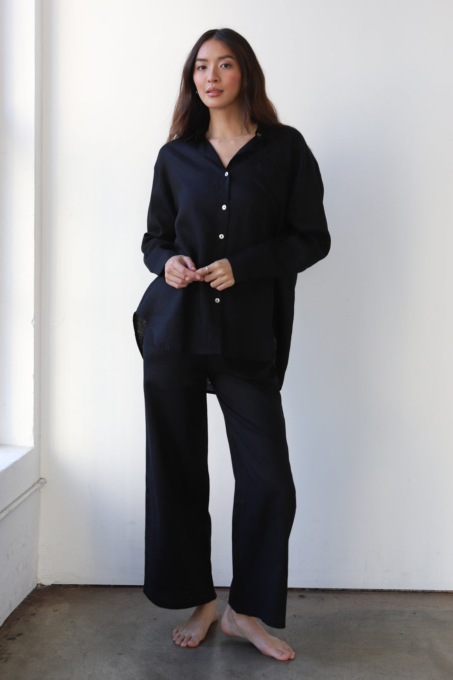 Full-length studio portrait of a model posing in the matching Be Idle black linen button-down shirt and wide-leg drawstring pants set.