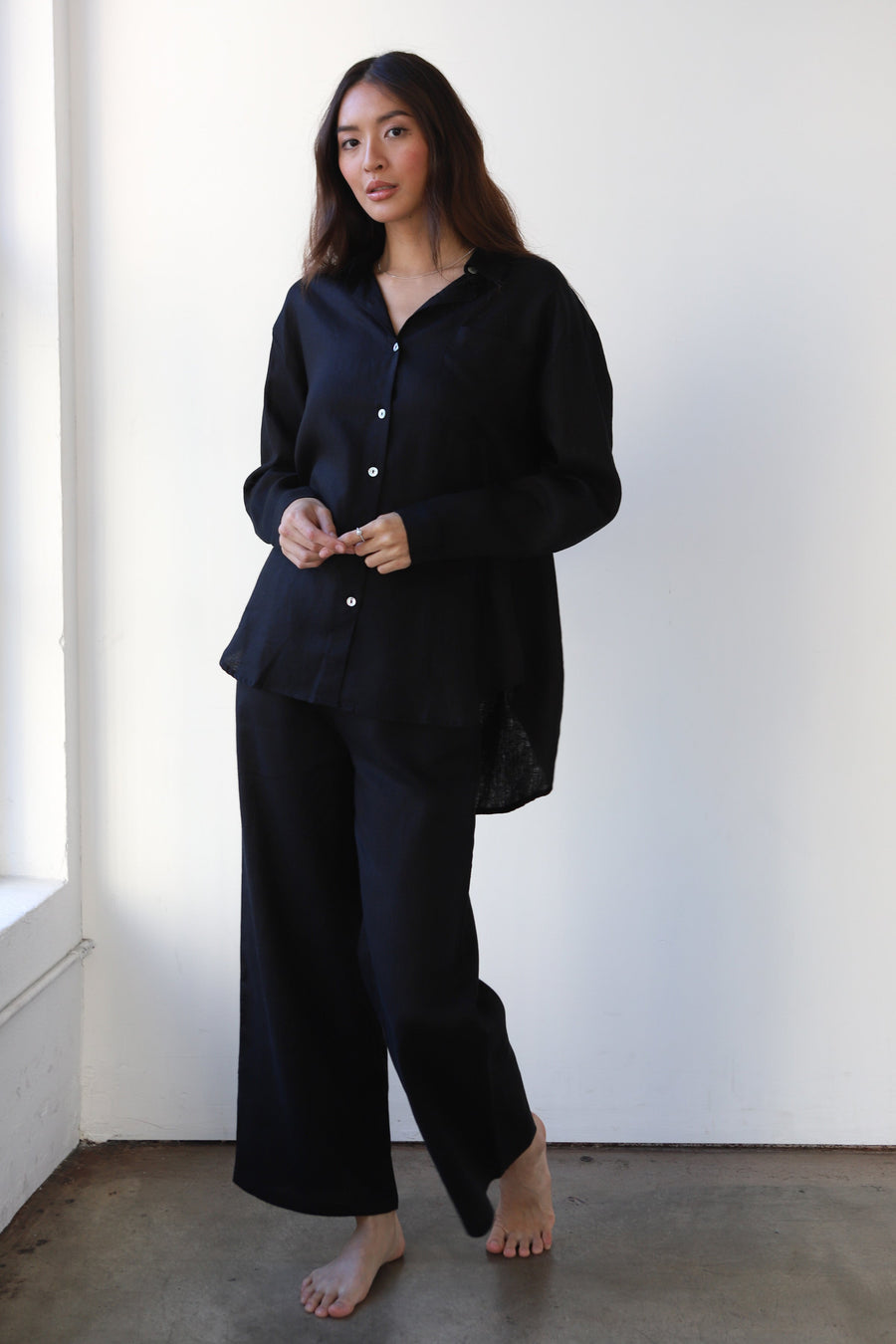 Full-length front studio shot of a model wearing the relaxed-fit black linen pants and long-sleeve linen top set.