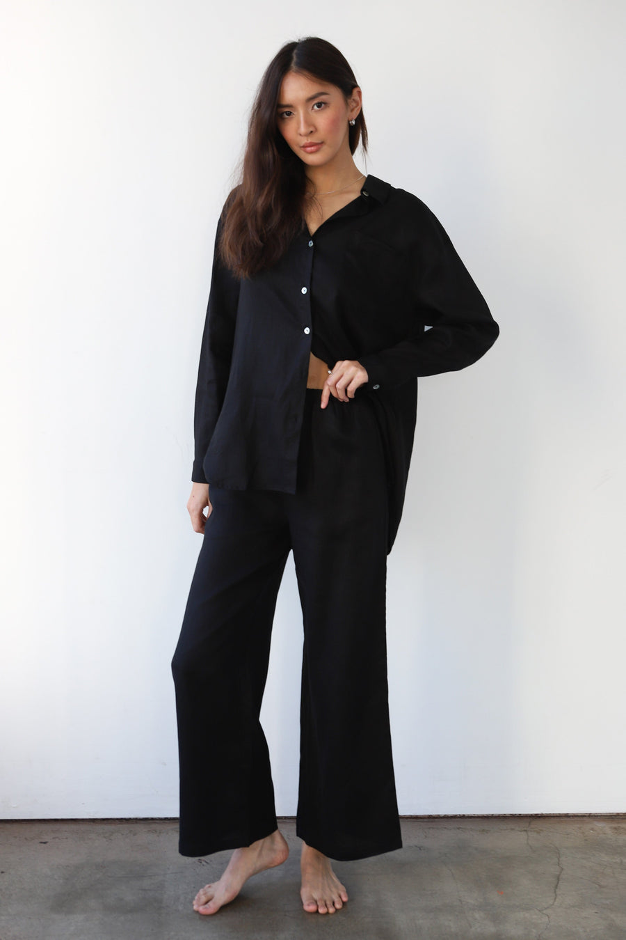 Full-length front studio shot of a model wearing the relaxed-fit black linen pants and long-sleeve linen top set.