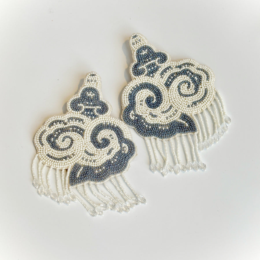 Flat lay view of the CLOUD hand-embroidered beaded cloud earrings showing velvet backing and glass beadwork.