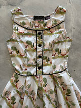 Flat lay detail of the Retrolicious Woodland Sunset dress bodice featuring front black non-functional buttons, black contrast piping, and brand tag.