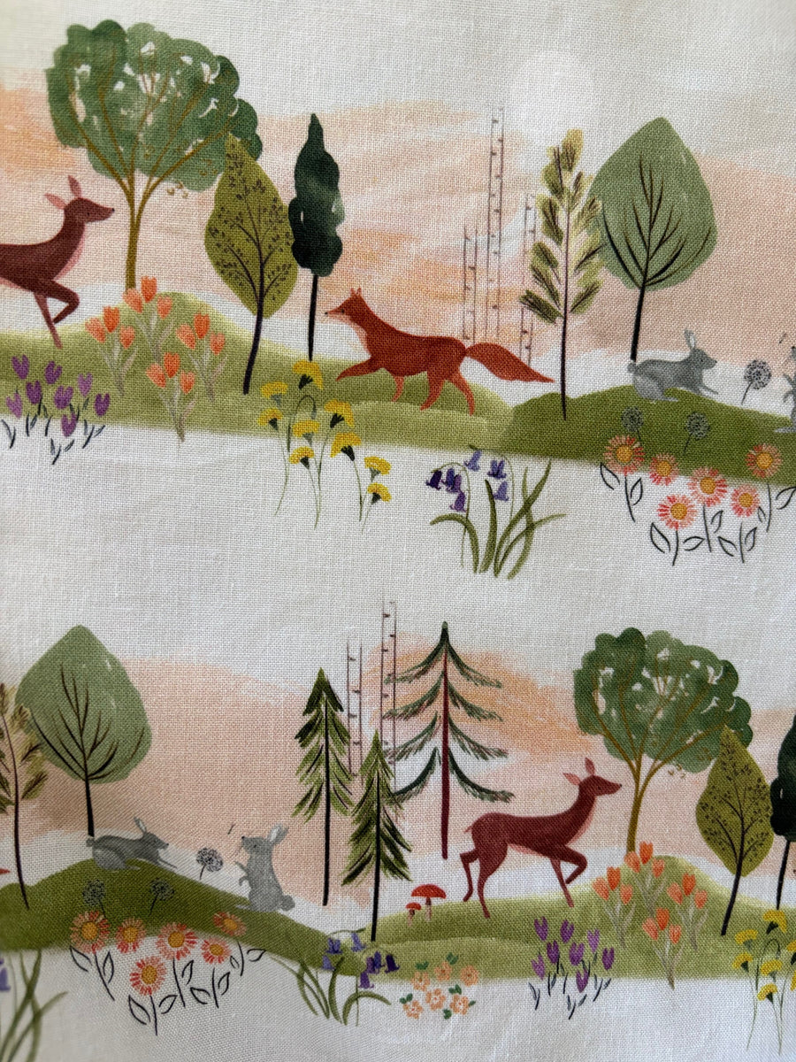 Close-up pattern detail of the Retrolicious Woodland Sunset print showing illustrated deer, foxes, rabbits, and trees on cotton fabric.