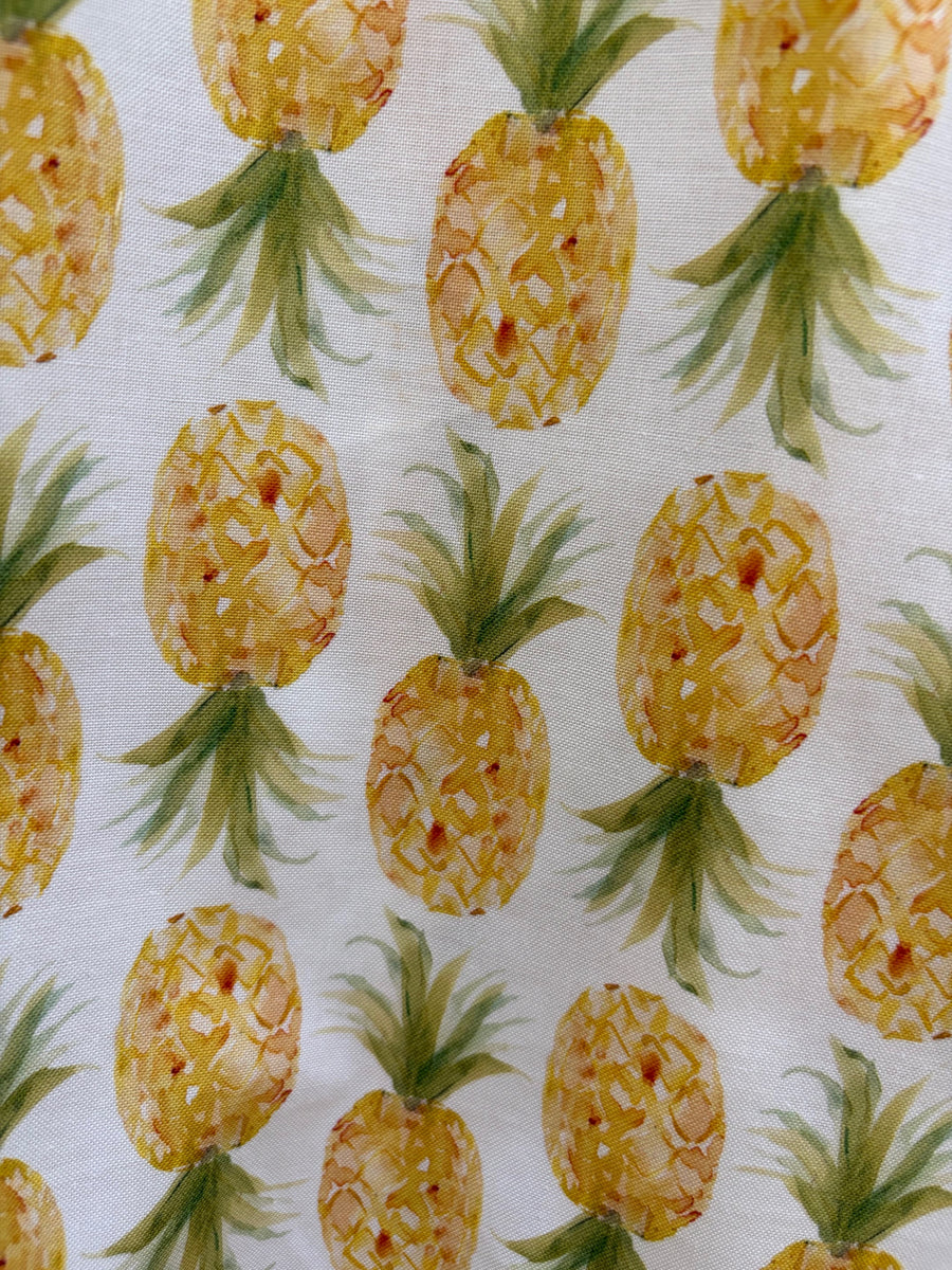 Close-up fabric print detail of the Retrolicious Pineapple Skater Dress showing yellow and green watercolor pineapples on white cotton.