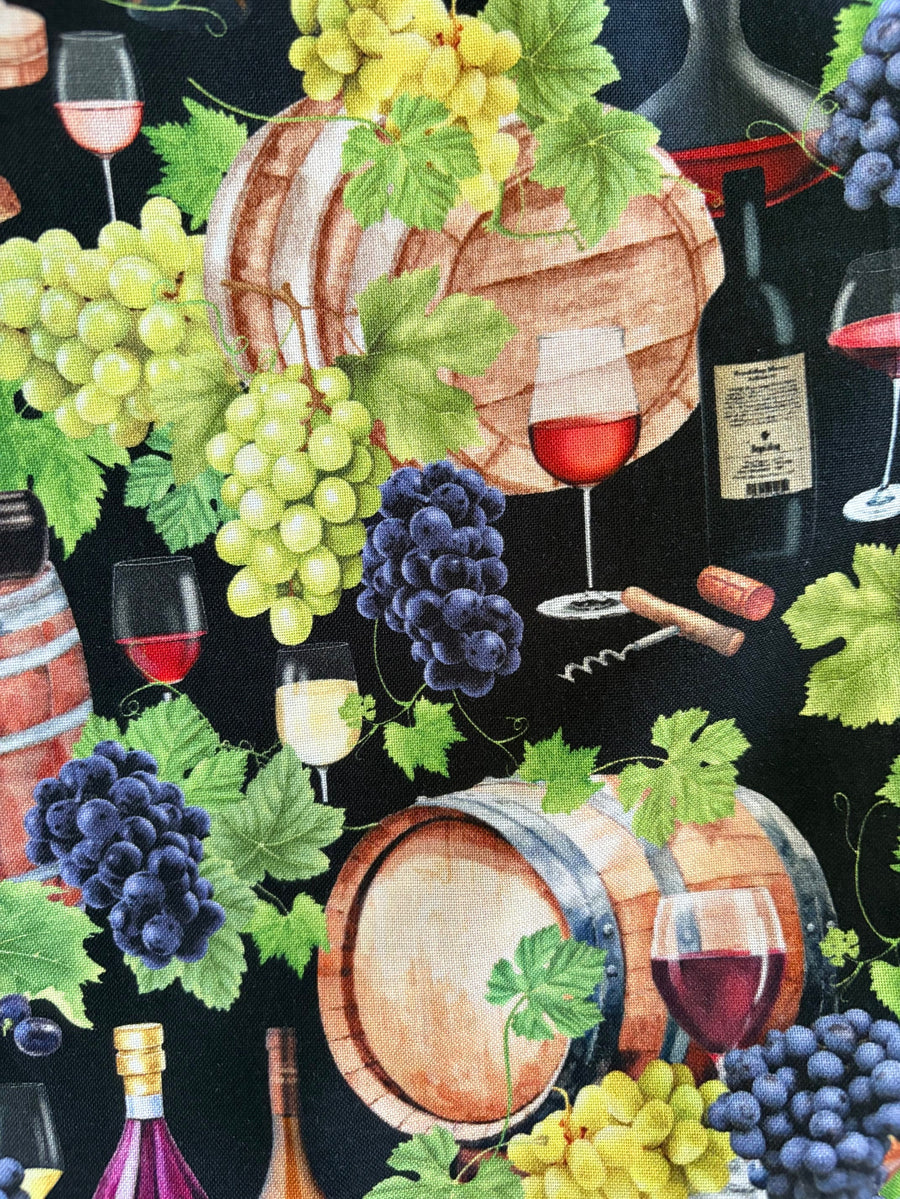 High-resolution detail shot of the 100% cotton fabric showing the wine bottle, oak barrel, wine glass, and green grape print.