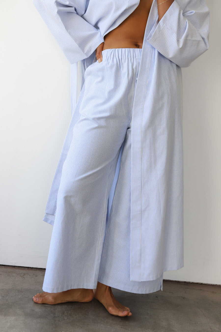 Close-up of a model wearing Be Idle The Pinstripe Boxer Pant in Sky, showing the relaxed wide-leg fit, and comfortable elastic waistband. Part of a size-inclusive cotton-blend loungewear collection.