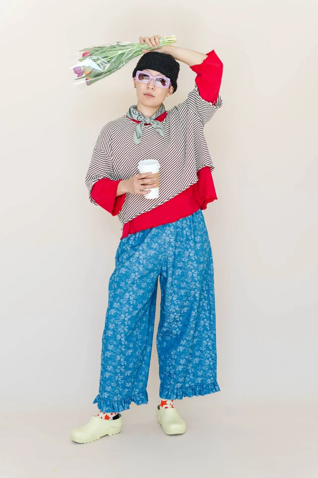 Full-body view of model styling the Nettle Studios striped oversized cropped tee with blue patterned trousers and clogs.