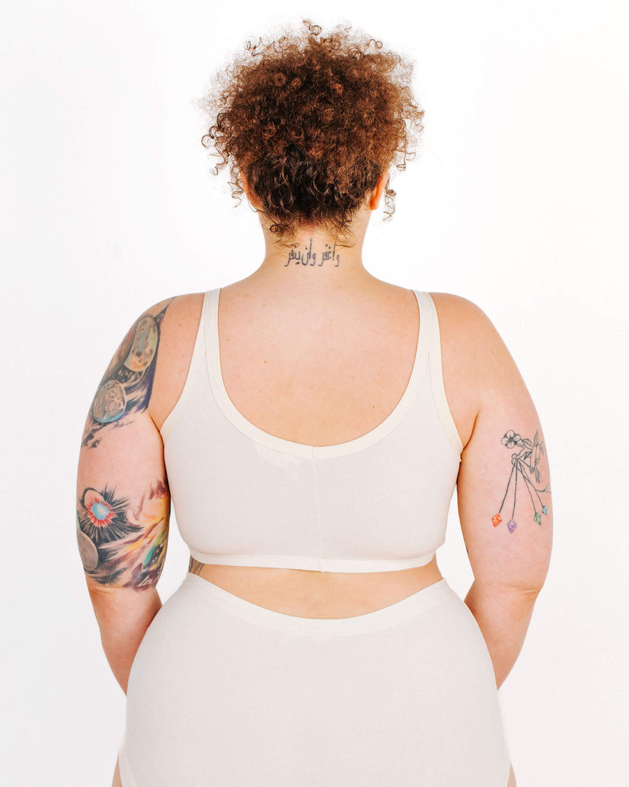 Rear portrait of a curly-haired model showing the scoop back fit and neck tattoo wearing a longline bra.