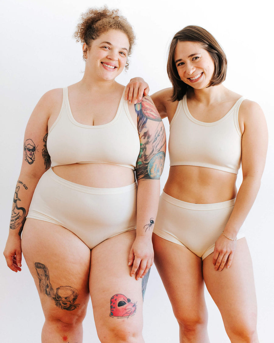 Full-length studio portrait of two diverse models posing in matching organic cotton longline bra sets.