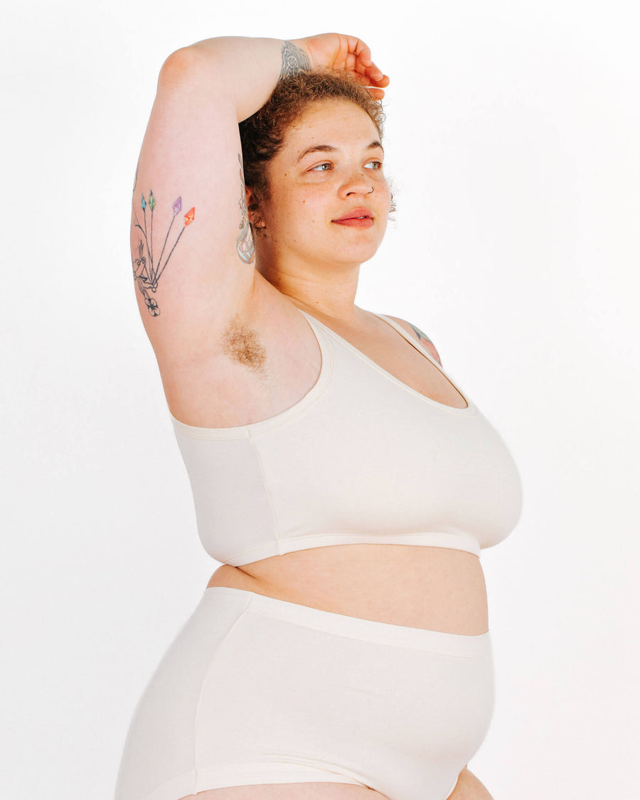 Side view of a curly-haired model showcasing the underarm fit and side coverage of a longline bra.