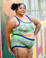 Three-quarter length view of a model posing outdoors in the green and pink Electric Tiger matching loungewear set.