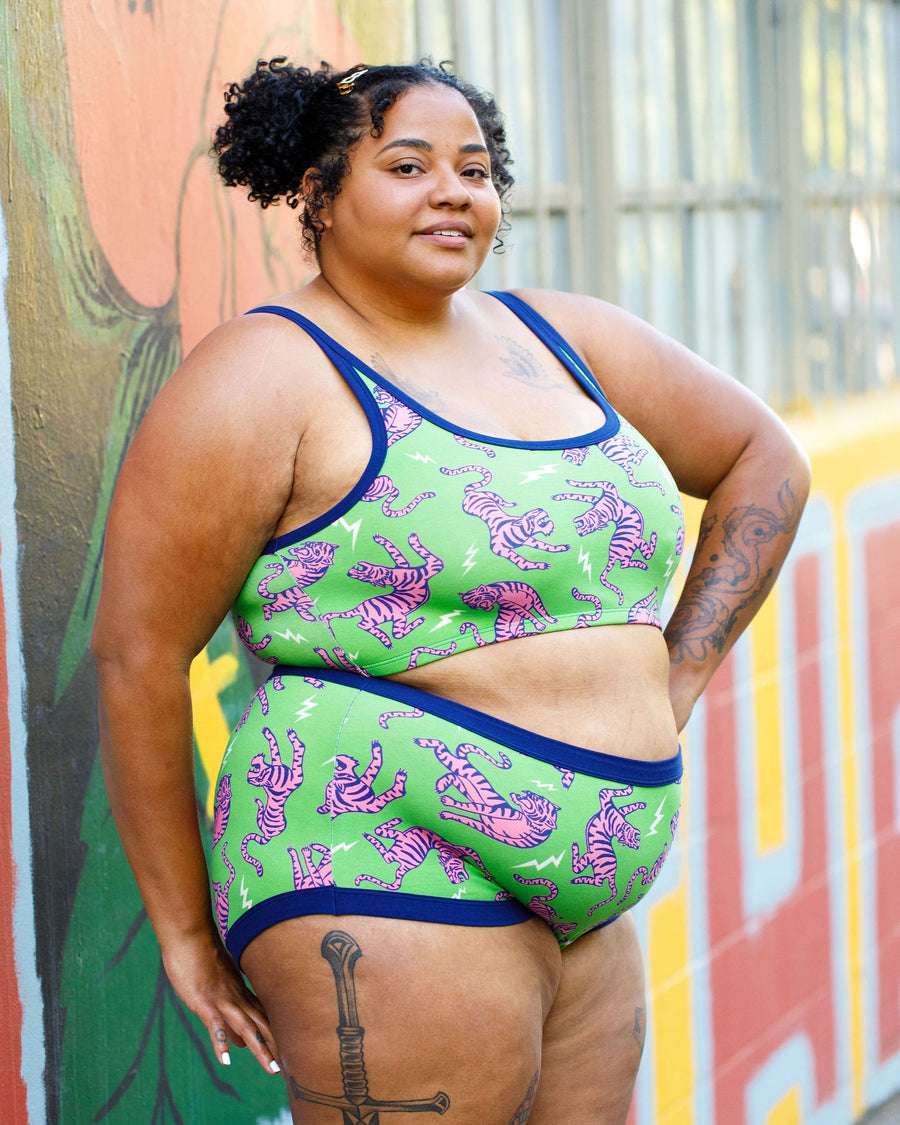 Three-quarter length view of a model posing outdoors in the green and pink Electric Tiger matching loungewear set.