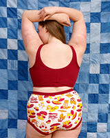 Rear view portrait of a model showcasing the scoop back fit and flat bottom band of the Tuscan Red longline bra.