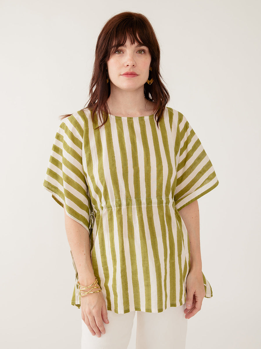 Model wearing the Mata Traders Darcey Kaftan Top in Green Stripe, a handmade, summer-weight olive green and cream vertical striped cotton kaftan shirt with an adjustable drawstring waist and wide, flowing sleeves.