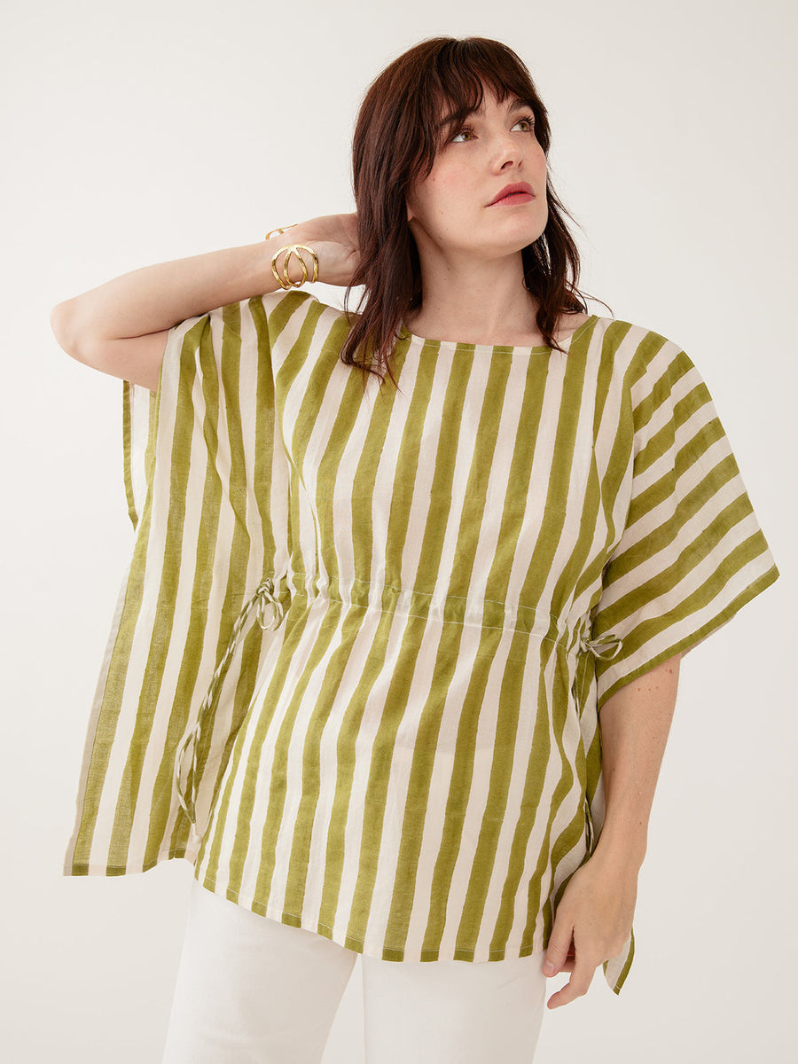 Model wearing the Mata Traders Darcey Kaftan Top in Green Stripe, a handmade, summer-weight olive green and cream vertical striped cotton kaftan shirt with an adjustable drawstring waist and wide, flowing sleeves.