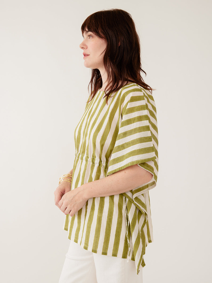 Model wearing the Mata Traders Darcey Kaftan Top in Green Stripe, a handmade, summer-weight olive green and cream vertical striped cotton kaftan shirt with an adjustable drawstring waist and wide, flowing sleeves - side view