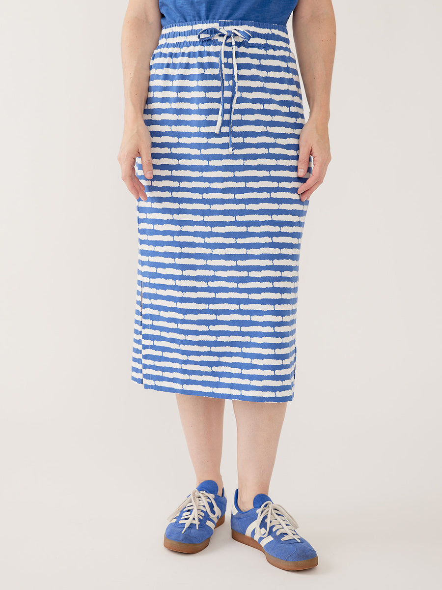 Model wearing the Mata Traders Isla Skirt in cobalt blue and white split stripe, styled with a solid blue top and blue sneakers.