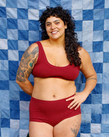 Front view studio portrait of a smiling model with tattoos posing in the Tuscan Red Thunderpants US matching underwear set.