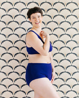 Side profile shot of a model posing in the Indigo Montoya deep blue organic cotton briefs and matching bra set.