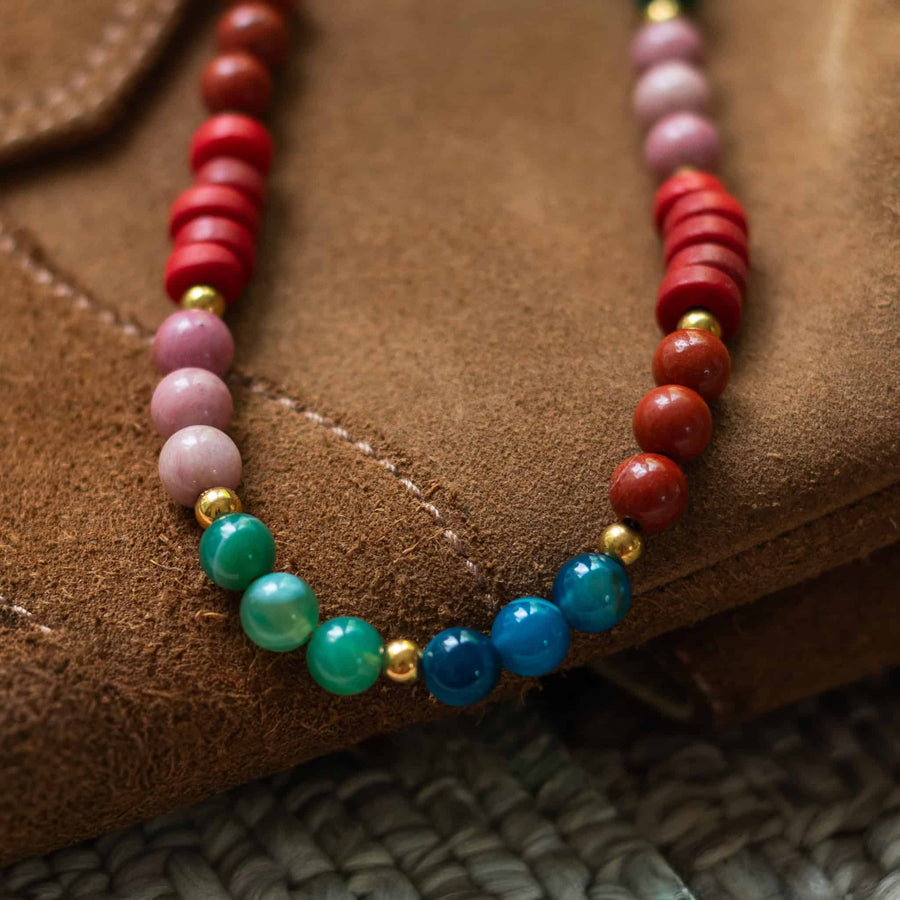 Close-up detail shot showcasing the texture and warm tones of the jade, jasper, and recycled glass beads resting on brown suede.
