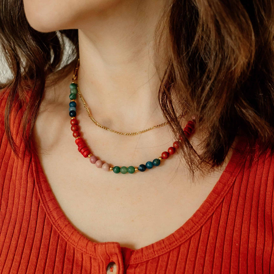 Model wearing the Phoebe Gemstone Necklace layered with a thin gold chain against a ribbed terracotta top.