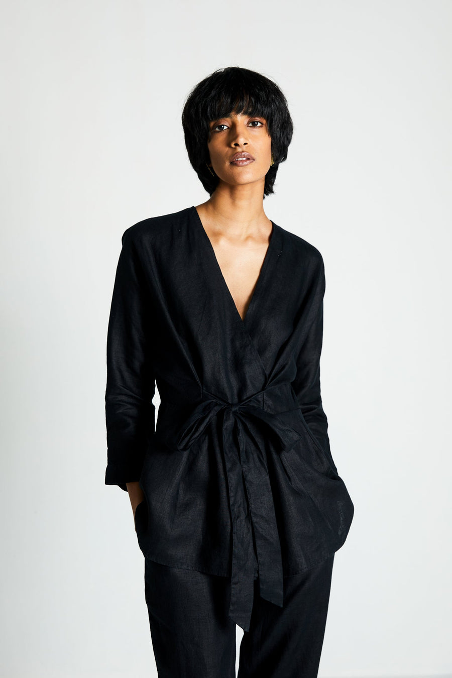 Front view of the black Reistor Power Moves hemp shirt, featuring a tailored wrap design with an adjustable waist tie. Shown on a model against a white studio background for a size-inclusive fashion campaign.