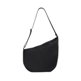 Studio side profile view of the STATE Bags Luna Crossbody in black showing its curved base and adjustable strap.