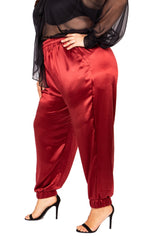 Side profile view of a model placing her hand in the side pocket of the burgundy wine silk jogger pants by Sante Grace.