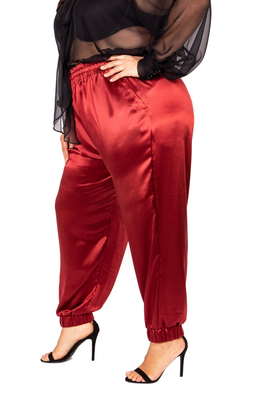 Side profile view of a model placing her hand in the side pocket of the burgundy wine silk jogger pants by Sante Grace.