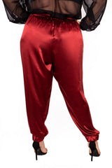 Rear view close-up of a plus-size model wearing burgundy wine high-waisted Italian silk jogger pants with elastic cuffed hems.