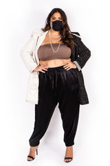 Front view of a model posing with hands on hips wearing black Sante Grace high-waisted Italian silk joggers styled with heeled sandals.