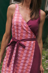 Front close-up of the Rove Dress in Hibiscus highlighting the deep V-neckline, waist tie bow, and contrast between the woven pink stripe pattern and solid magenta bodice.