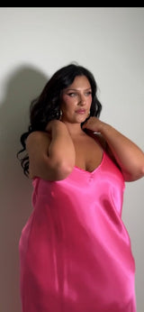 Front portrait of a brunette plus-size model posing with her hands behind her neck, wearing the bright pink Best Curve bias cut bamboo slip dress.