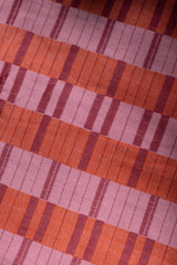 Macro close-up of the handwoven cotton fabric showing the geometric block pattern in pink, orange, and magenta shades on the Rove Dress.