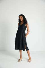 Full-body studio shot of a model standing with her hand in her pocket, highlighting the hidden side insert details and practical pocket construction of the black Hemp Noir dress.