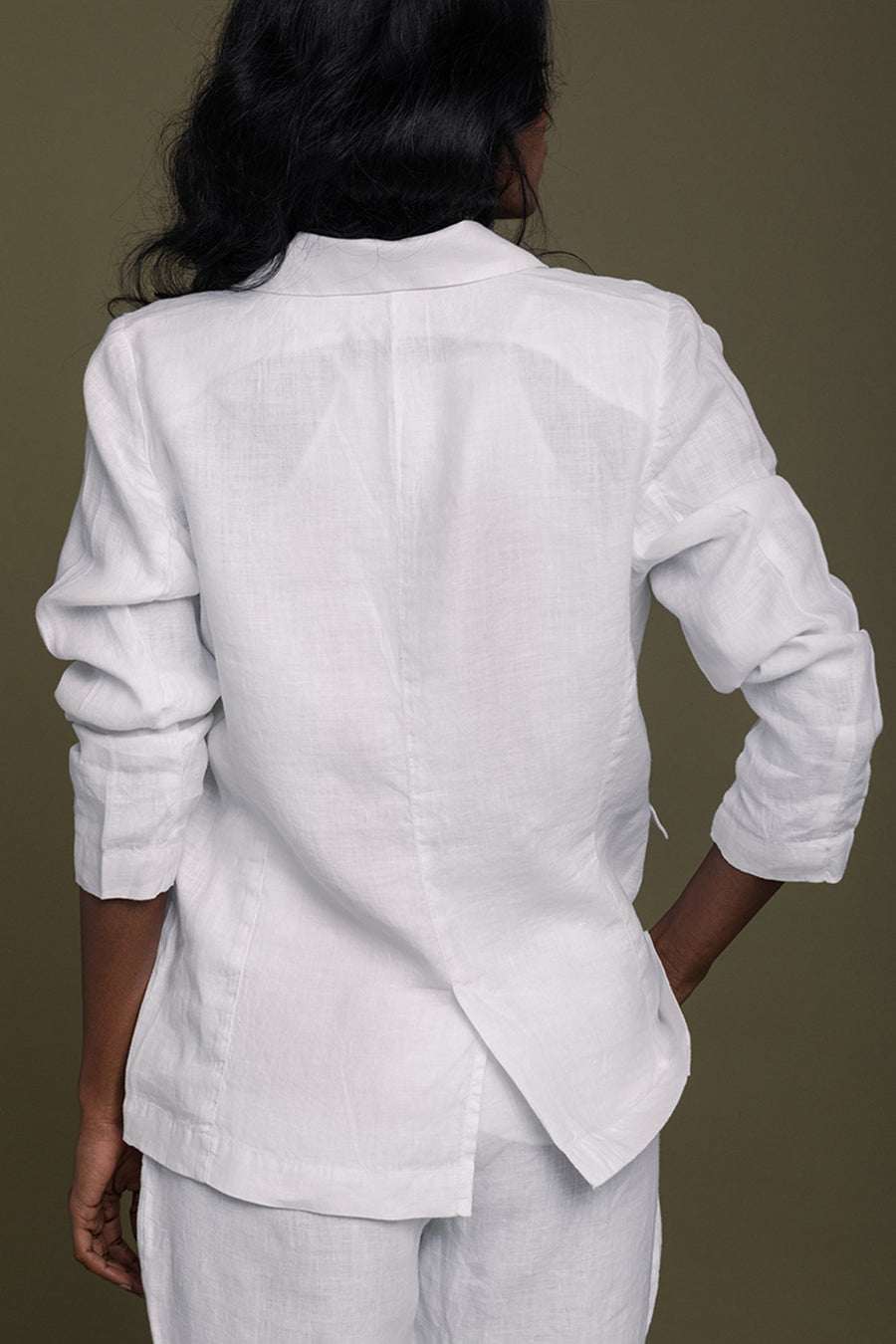 Back profile view of the white hemp blazer on a model, highlighting the clean center seam, tailored back vent slit, and comfortably bunched long sleeves.