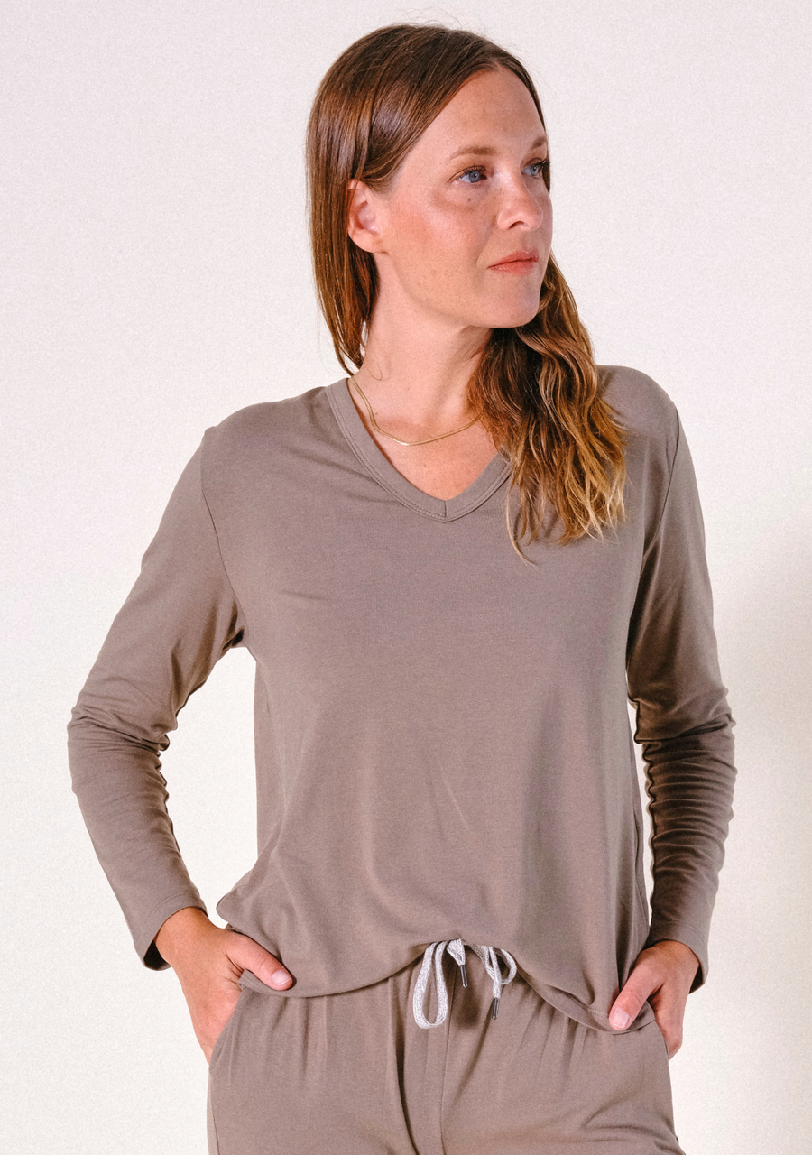 Three-quarter front shot of a model wearing the olive-brown Poplinen Toni Pajama Shirt with hands in her pant pockets.
