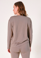 Rear view portrait of a model wearing the olive-brown long-sleeve Poplinen Toni Pajama Shirt.