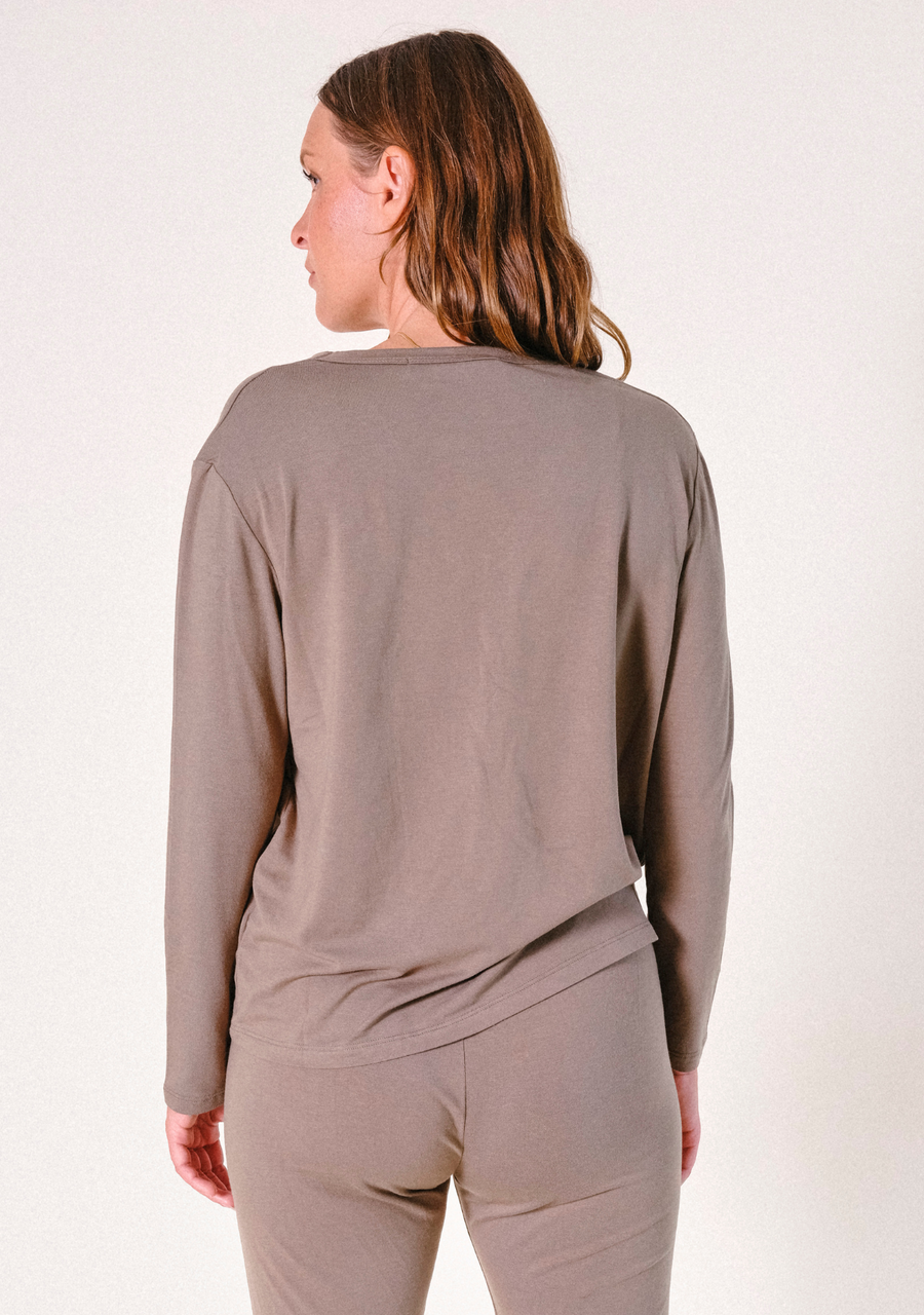 Rear view portrait of a model wearing the olive-brown long-sleeve Poplinen Toni Pajama Shirt.